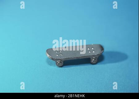 figurine métallique d'un mannequin de skateboard sur un fond bleu clair avec une ombre dure. Banque D'Images
