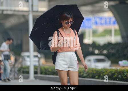 Wuhan: Jeune femme chinoise qui protège du soleil avec un parapluie à la sortie de la station de métro Chuhe Hanije, rue Zhong Boi lu. Chine Banque D'Images