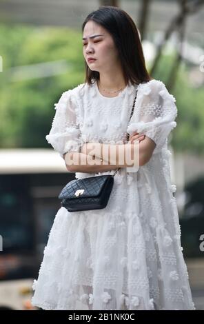 Wuhan: Une jeune femme avec une robe blanche et un sac à main noir attendant à la sortie de la station de métro Chuhe Hanije, rue Zhong Boi lu. Chine Banque D'Images