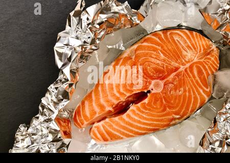 Placer horizontalement le steak de saumon sur du papier aluminium avec de la glace. Banque D'Images