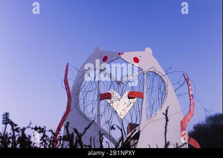 Carte postale adaptée à la Saint-Valentin, une figure deux souris avec des queues longues dans le baiser en plein air et tenir ensemble un coeur par leurs pattes contre un lilas Banque D'Images