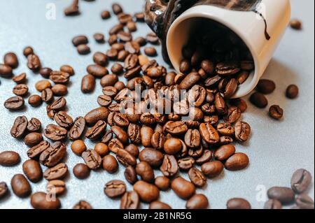 photo prête à l'emploi pour la publicité du café et prête à la publication, un grand nombre de grains de café torréfiés sont dispersés autour d'un mug blanc plein de b Banque D'Images