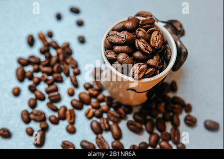 photo prête à l'emploi pour la publicité du café et prête à la publication, un grand nombre de grains de café torréfiés sont dispersés autour d'un mug blanc plein de b Banque D'Images