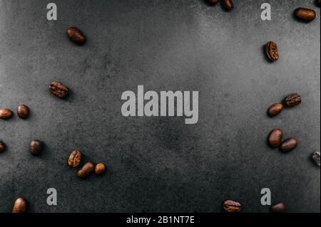 grains foncés frits dispersés de café arabica sur un fond uniforme dans le style de noir total minimal Banque D'Images
