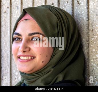 Un portrait d'une jeune femme musulmane attrayante et souriante aux yeux bruns magnifiques porte un hijab vert foncé sur un fond neutre. Banque D'Images