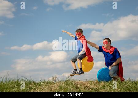 Père et fils jouer au super-héros de la journée. Les gens s'amuser en plein air.Ils sauter sur des ballons gonflables sur la pelouse. Concept de famille accueillante. Banque D'Images