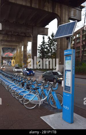 Vélos à louer près de l'entrée du marché public de Granville Island. Station de paiement à énergie solaire au premier plan. Banque D'Images