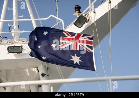 Drapeau rouge blanc et bleu de l'Australie volant un jour bleu dans des vents forts sur un mât de bateau de croisière Banque D'Images