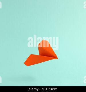 Plan en papier orange flottant sur fond vert menthe Banque D'Images