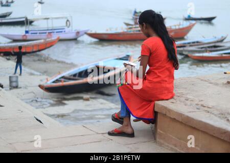 La femme indienne est assise seule sur la rive du Ganga River Banque D'Images