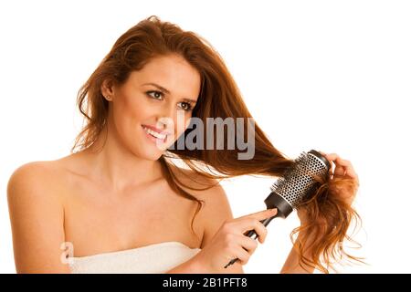 Belle jeune femme peignait ses cheveux avec une brosse isolée sur fond blanc Banque D'Images