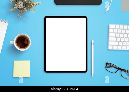 Poche de tablette sur le bureau entouré de stylo, tasse de café, clavier, usine, tablette et lunettes. Tablette moderne avec bords ronds et fins Banque D'Images