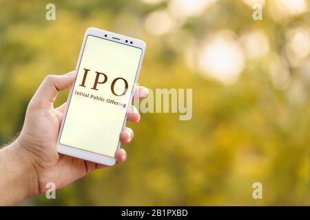 Concept D'Offre Publique Initiale. Main jeune homme tenant le téléphone mobile et montrant IPO qui est affiché à l'écran en arrière-plan extérieur avec copie Banque D'Images