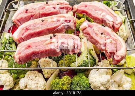 Assortiment de légumes frais sur un plateau de cuisson viande de porc brute sur le gril. Chou-fleur, brocoli, betterave, courgettes. Concept de nourriture saine. Boar en bois Banque D'Images