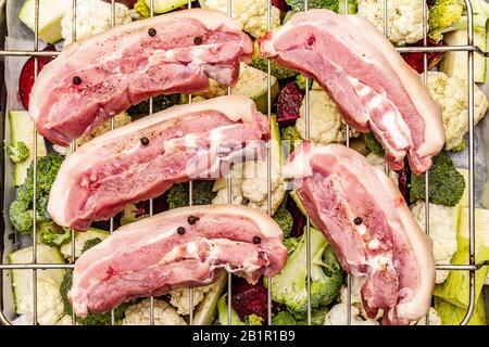 Assortiment de légumes frais sur un plateau de cuisson viande de porc brute sur le gril. Chou-fleur, brocoli, betterave, courgettes. Concept de nourriture saine. Boar en bois Banque D'Images