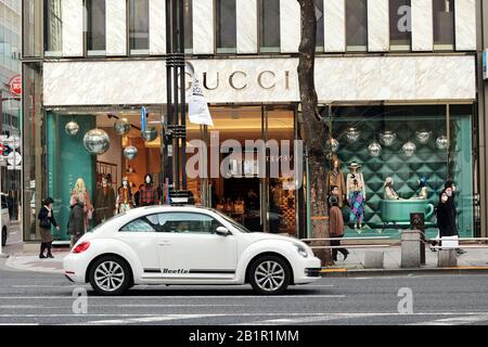 Une Volkswagen Beetle moderne passant devant un magasin Gucci dans la région de Ginza à Tokyo. Un flou de mouvement. Banque D'Images