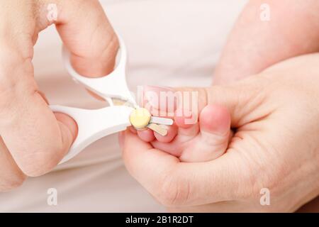 La mère utilise des ciseaux spéciaux pour ongles de bébé pour couper les ongles du bébé nouveau-né Banque D'Images