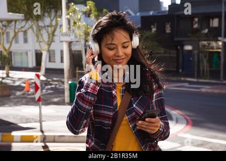 Femme écoutant de la musique dans la rue Banque D'Images