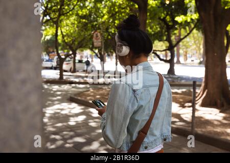 Femme écoutant de la musique dans la rue Banque D'Images