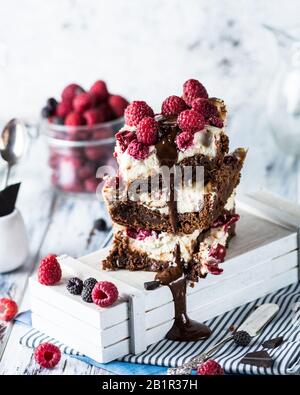 Cheesecake brownies avec framboises empilées sur une plaque. Chocolat fondu. Morceau de gâteau. Dessert Brownie. Cerise et framboise. Saint Valentin. Banque D'Images