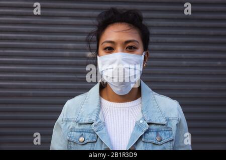 Femme portant un masque de visage de virus Corona et regardant l'appareil photo Banque D'Images