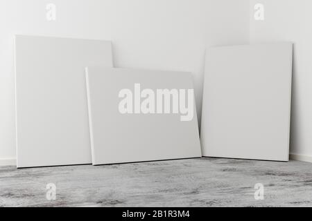 Plusieurs cadres photo vides s'inclinent contre le mur blanc dans une pièce lumineuse avec un sol en béton gris avec espace de copie - portfolio, galerie ou tout-en-un Banque D'Images
