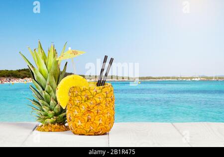 Jus d'ananas servi dans la pelure sur table en bois blanc Banque D'Images