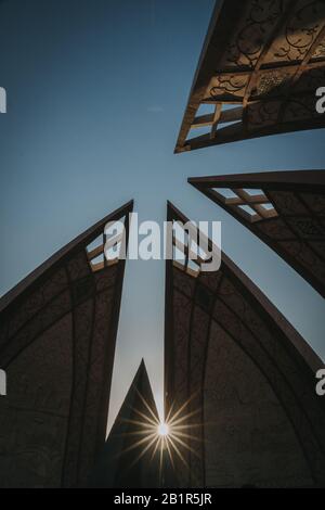 Sunburst à travers la silhouette angulaire d'un monument au Pakistan au crépuscule dans un fond architectural Banque D'Images