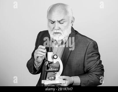 Travail de doctorat et postdoctoral de l'emploi. Professeur expérimenté de la biologie. Projets doctorat de biologie moléculaire. Homme mature costume formel avec microscope. Le professeur chargée de cours à l'université. Expert scientifique en microbiologie. Banque D'Images