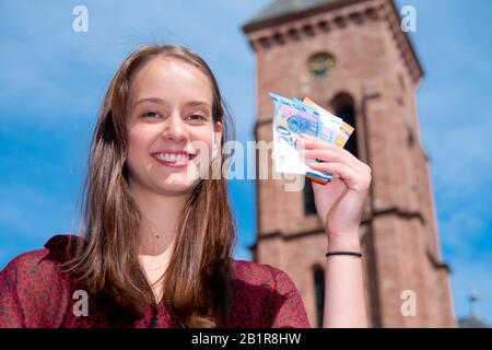 Jeune femme devant un chruch, tenant des factures d'Euro dans sa main - taxe d'église, Allemagne Banque D'Images