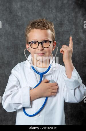 Mignon enfant garçon porter uniforme de médecine jouant médecin, un portrait Banque D'Images