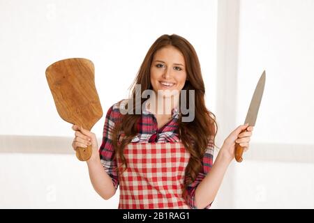 belle jeune femme tenant bord et couteau en bois dans la cuisine Banque D'Images