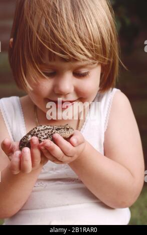 jeune enfant, petite fille, tenant un crapaud dans ses mains Banque D'Images