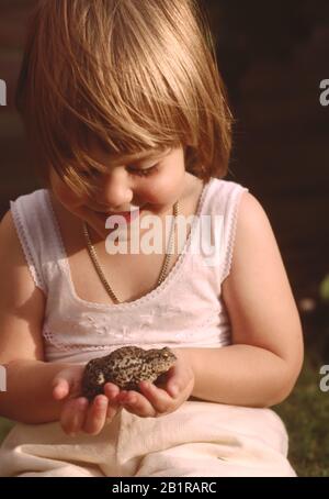 jeune enfant, petite fille, tenant un crapaud dans ses mains Banque D'Images