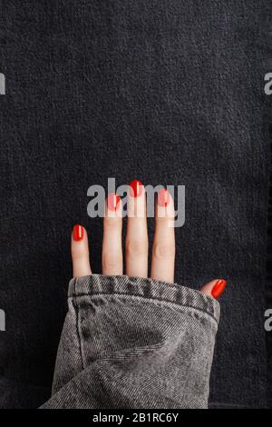 Ouvrez la main avec une manucure rouge brillante sur un fond de jeans. Placer pour le texte Banque D'Images