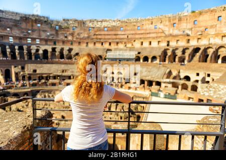 Le touriste féminin aux cheveux dorés regarde le Colisée de Rome, en Italie. Le Colisée est un monument important de l'antiquité et est l'un des principaux tou Banque D'Images