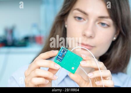 Femme Jeune scientifique en laboratoire microbiologique avec lab-on-chip LOC microfluidic device Banque D'Images