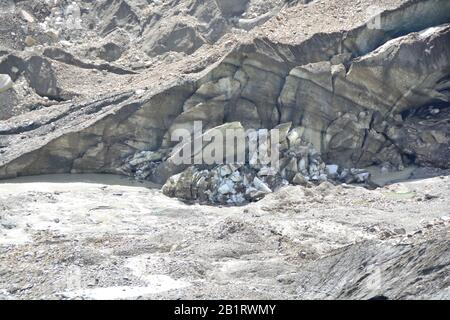 Le museau d'un glacier transportant de la morraine, avec de grands blocs de glace brisés et une rivière en eau de fonte s'écoulant Banque D'Images