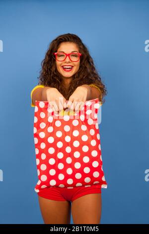 Veautiful jeune femme avec des sacs de shopping et carte de crédit sur fond bleu Banque D'Images