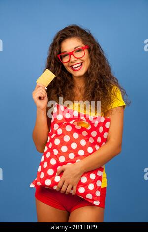 Veautiful jeune femme avec des sacs de shopping et carte de crédit sur fond bleu Banque D'Images