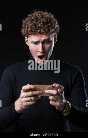 Portrait d'un jeune homme d'affaires bien enlisé et séduisant se tenant face à l'arrière-plan noir Banque D'Images