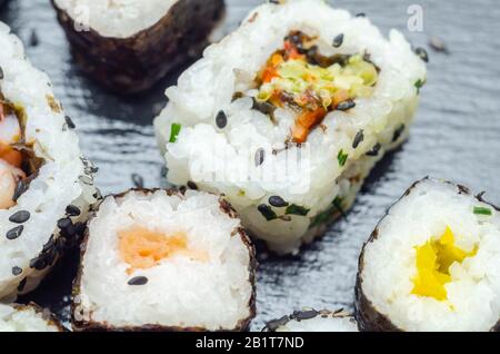 Mélangez les sushis veggie et les sushis de poisson sur la plaque en pierre noire, la nourriture japonaise Banque D'Images