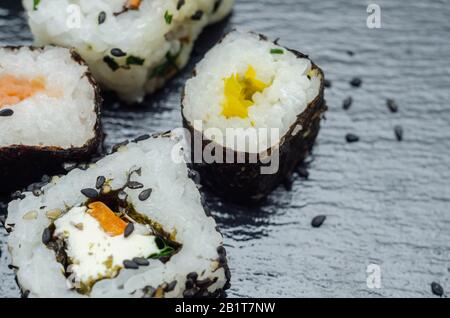 Mélangez les sushis veggie et les sushis de poisson sur la plaque en pierre noire, la nourriture japonaise Banque D'Images