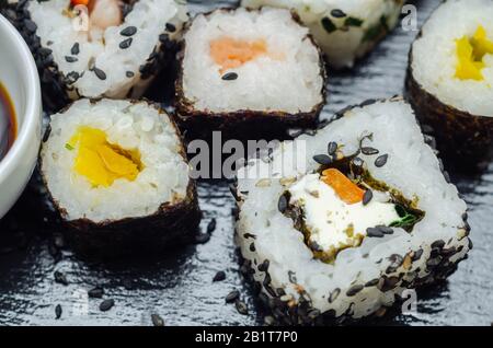 Mélangez les sushis veggie et les sushis de poisson sur la plaque en pierre noire, la nourriture japonaise Banque D'Images