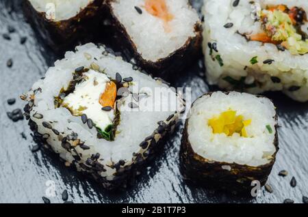 Mélangez les sushis veggie et les sushis de poisson sur la plaque en pierre noire, la nourriture japonaise Banque D'Images