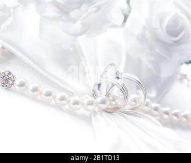 Anneaux de mariage incrustés de perles, isolés sur un fond blanc doux, horizontaux presque noir et blanc. Banque D'Images