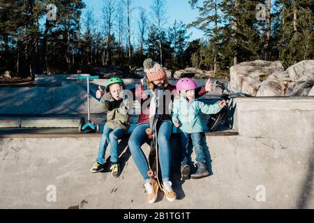 maman jouant avec ses enfants dans un parc de skate s'amuser Banque D'Images