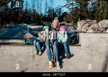 maman jouant avec ses enfants dans un parc de skate extérieur en s'amusant Banque D'Images