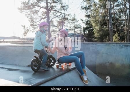 maman et fille jouant et riant dans un parc de skate au soleil Banque D'Images