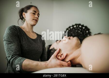 le patient de massage masculin a le cou travaillé par la femme massothérapeute Banque D'Images